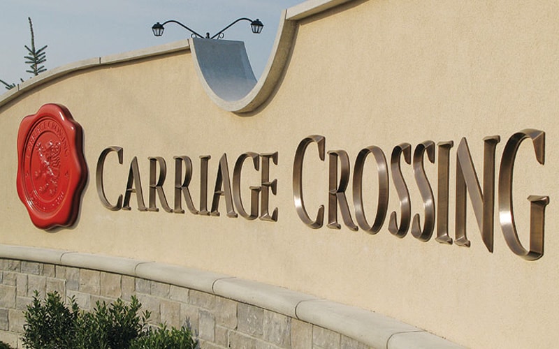 brushed oxidized oil rubbed bronze letters mounted on stucco monument for neighborhood entrance