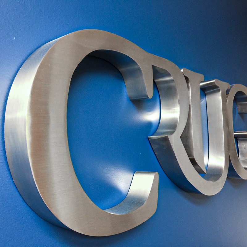 thick brushed stainless steel metal letters mounted on blue inteior lobby wall