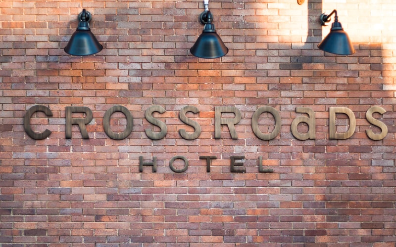 oxidized oil rubbed bronze letters mounted outside on brick wall for hotel with gooseneck lighting