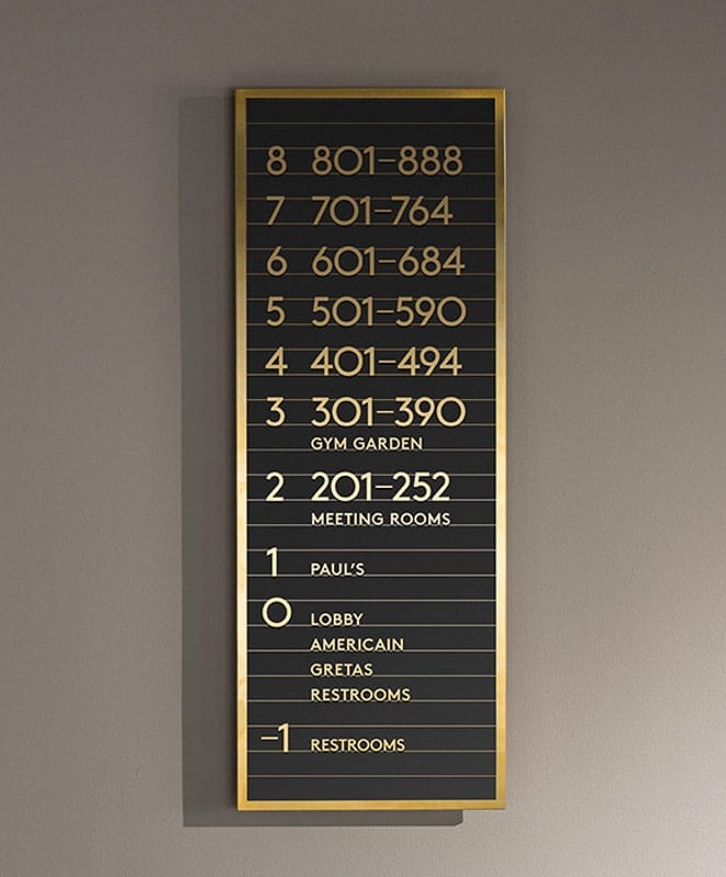 bronze rectangular plaque with gold lettering on plain white wall